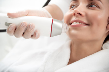 Close up beautician hand keeping special equipment. Outgoing girl getting treatment of skin on...