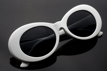 oval sunglasses in white plastic frame isolated on black