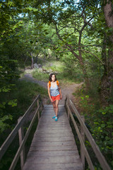 Fototapeta premium The girl is walking along the wooden bridge.