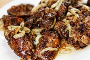 Fried chicken's livers on white plate on a wooden table
