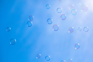 Soap bubbles in flight against the blue sky