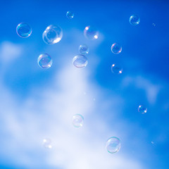 Soap bubbles in flight against the blue sky