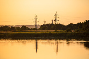 Electric pillar with reflection in the water at sunset