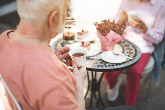 Focus on senior male holding cup of tea. He is sitting at table with wife and admiring dinner together