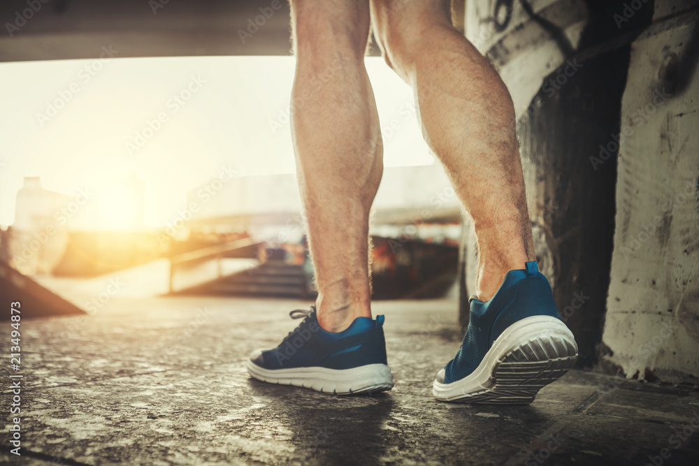 Wall mural close up of male feet in motion. muscular guy is training in snickers to stay fit