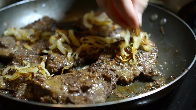 Juicy appetizing beef or pork meat or liver roasts in a frying pan. Concept of cooking. Close-up.