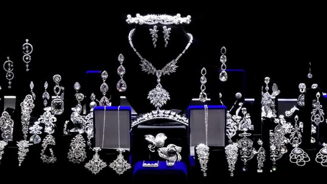 Showcase with diamond silver jewellery in motion over black background.