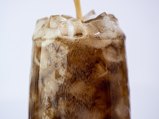 Selective fucus of pouring cola soft drink with ice in the glass on isolated / white background