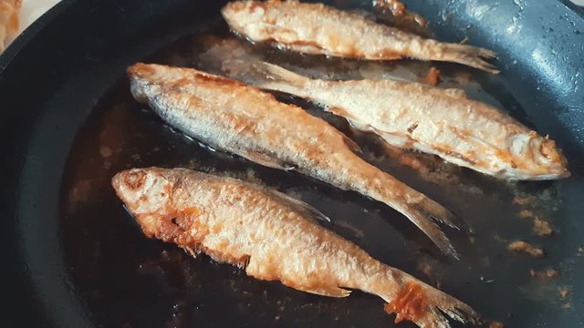 River fish frying on pan close up, dynamic scene, toned video. Delicious fresh food in the process of cooking.