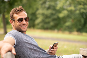 Fototapeta premium Mann draußen beim lachen und Smartphone in der Hand