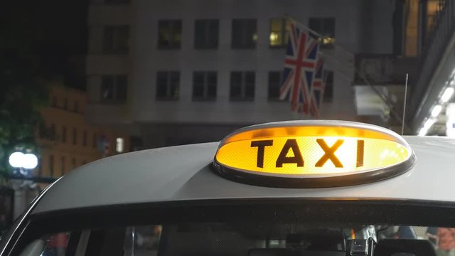 A taxi sign on a black cab. Flag of Britain. London at night.