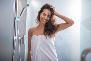 Portrait of outgoing woman standing after taking bath. She holding hair with hand