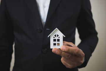 Businessman hand holding model white house. Property investment and house mortgage financial concept, Home protect, Insurance. With copy space for your text.