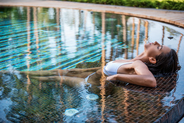 Side view orderly female having leisure in swimming pool outdoor. Calm lady during vacation concept