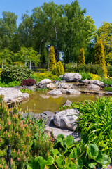 A small pond surrounded by huge stone boulders and decorative flower beds