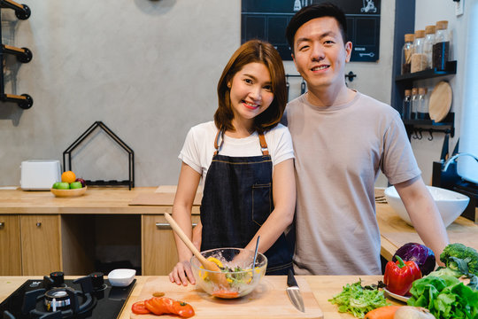 Asian couple prepare food together. Beautiful happy asian man and woman are cooking in the kitchen. Young asian couple have romantic time while staying at home. Couple lifestyle at home concept.