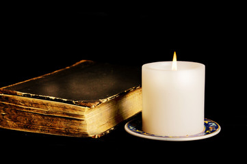 Magic book with candle over black background like esoteric and occult concept