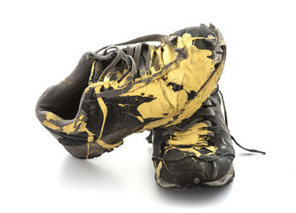 Pair of old paint covered training shoes on a white background