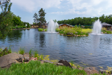 cascade of fountains on a lake with large stones on the banks on the blue sky background
