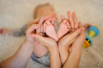 Naklejka premium Mother and father holding in their hands sleeping daughter feet