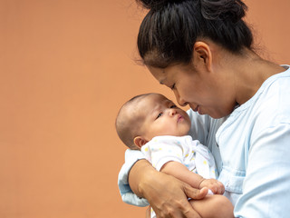 Portrait of happy Asia mother holding his newborn sweet baby dressed. The mommy embracing her baby...