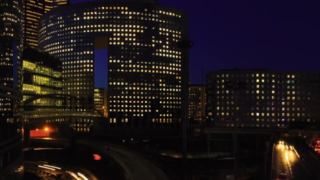 Time lapse of Paris modern buildings, dynamic urban street traffic, car lights in business district La Defense. Night cityscape with glass facade skyscrapers. Evening jam, economics, finance concept