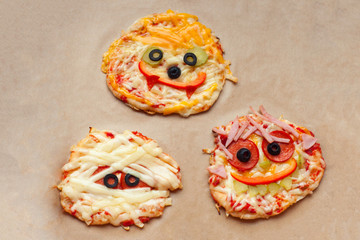 Halloween pizza with monsters, above scene with decor on a craft paper box background, idea for home party food, easy, healthy and delicious fun food party treats for kids