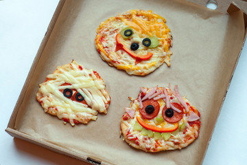 Halloween pizza with monsters, above scene with decor on a craft paper box background, idea for...