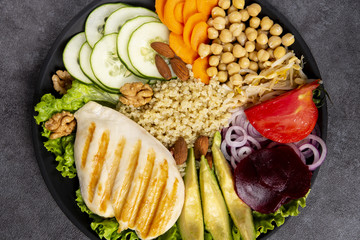 Bowl of Buddha, The concept of a healthy diet: grilled chicken, avocado, chickpeas, kinua, carrots, tomatoes, nuts. Balanced food. Top view. Copy space.