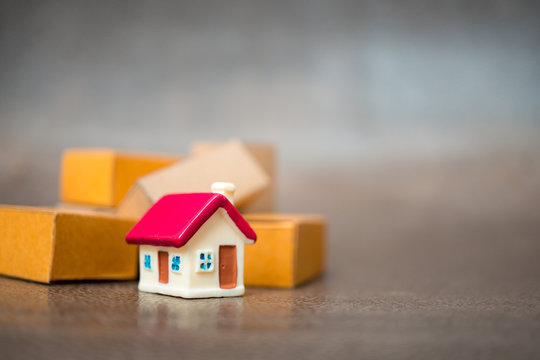 Miniature red house with paper box background using as property, e-commerce and business concept