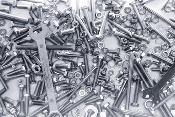 background of many different metal rivets, wrenchs, screws and bolts of silver and black color