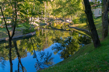 The pedestrian bridge in the park is reflected in the layout of a calm river