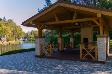 Beautiful wooden gazebo on the background of a large blue decorative lake