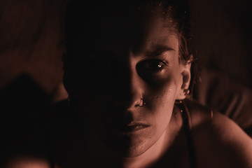 Portrait of a sad and angry woman with half lit face