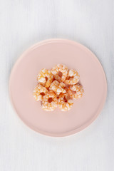 Fototapeta na wymiar Boiled shrimp on a pink plate. Macro. The concept of healthy eating. The background is white. Copy space. Vertical shot. Top view.