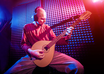 Obraz premium Young man playing on the bouzouki in sound recording studio.