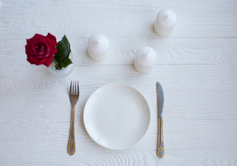 Romantic dinner concept. Valentine day or proposal background. Top view of restaurant wooden table with heart and rose with cutlery on plate. Copy space on rustic wood