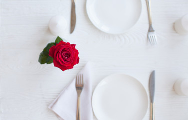 Vintage table setting with roses, antique rustic dishes and cutlery on the wooden background, close-up