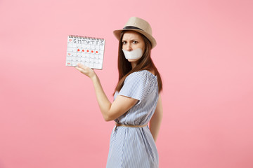 Portrait of woman holding female periods calendar for checking menstruation days, closed mouth with sanitary napkin isolated on pink background. Medical, healthcare, gynecological concept. Copy space.