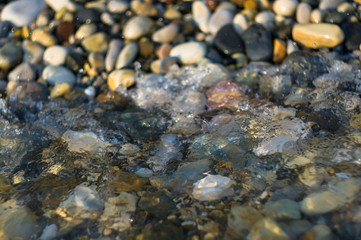 pebble stones on the sea beach, the rolling waves of the sea with foam