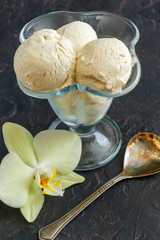 Vanilla ice cream in a vase and an orchid flower.