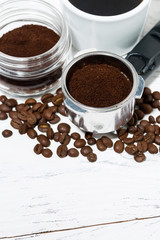 holder with ground coffee and cup of coffee on white background, vertical