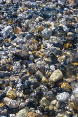 sea pebble beach with multicoloured stones, waves with foam