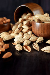 Peeled and unpeeled almond nuts in wooden bowls