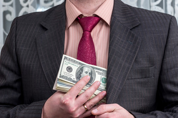 Businessman hiding dollar money into jacket pocket