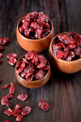 Dried cranberries in wooden bowls against the dark background