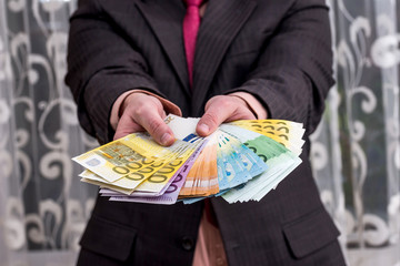 Businessman in suit with fan from euro banknotes