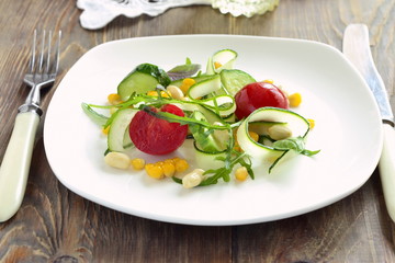 Fresh salad with zucchini, arugula, corn, cucumbers and tomatoes