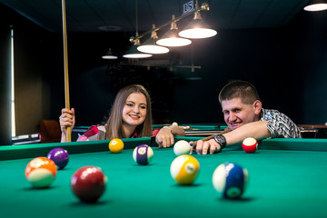 Fototapeta premium Friends playing billiard, man going hit a ball