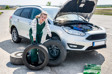 Woman with tyres on roadside with broken car